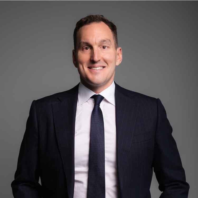 Headshot of Michael Tanner Smiling on a grey background